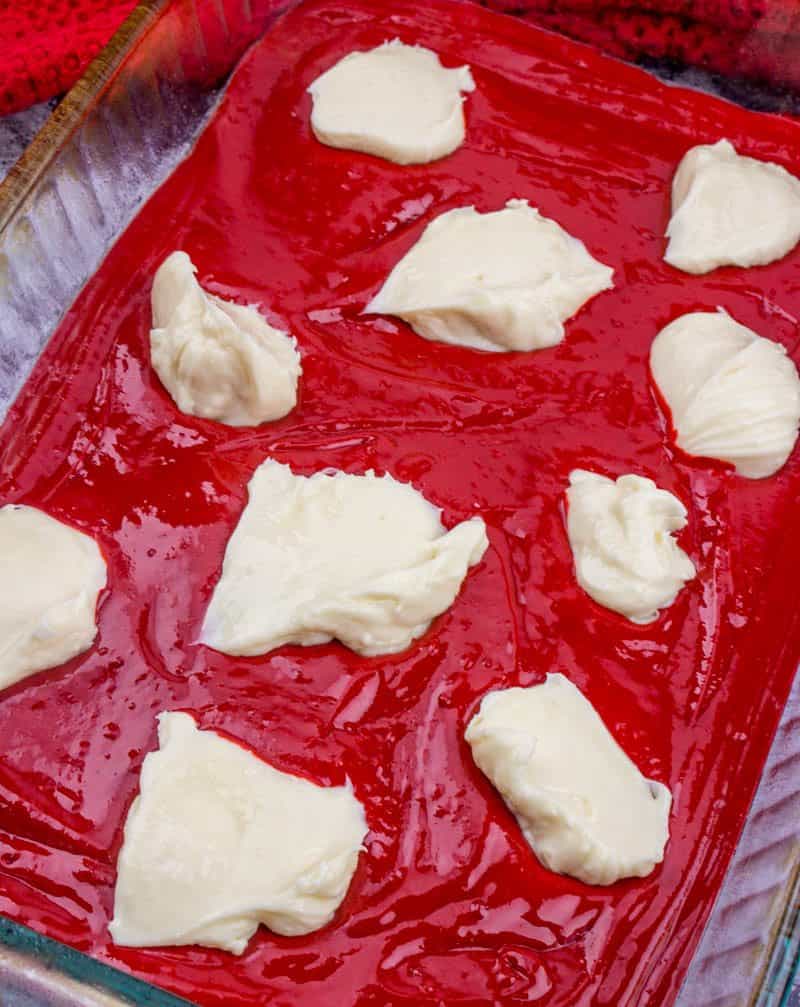 sweetened cream cheese mixture dolloped onto red velvet cake batter