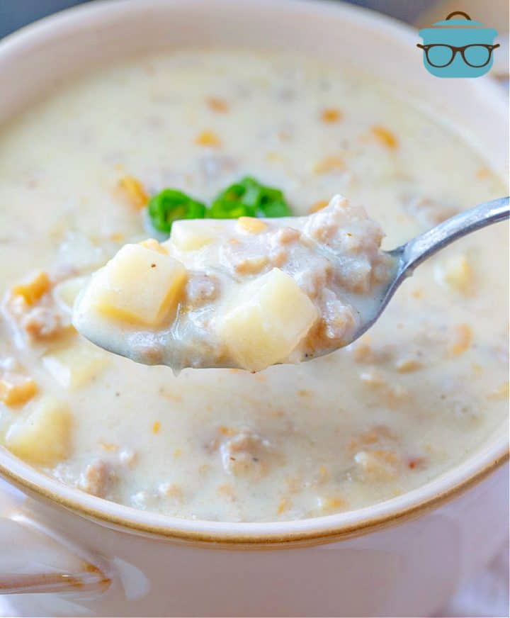 a spoonful of sausage corn chowder hovering over a bowl of soup.