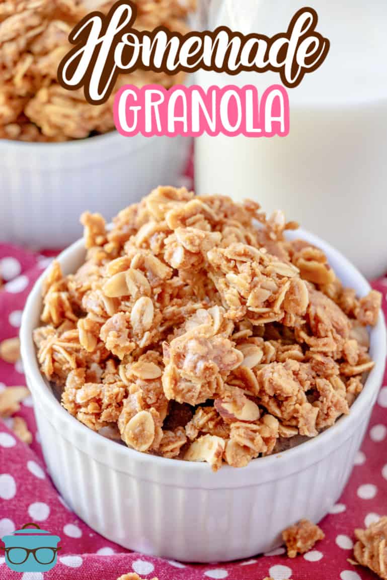 homemade granola shown in a small round white bowl with a bottle of milk in the background.