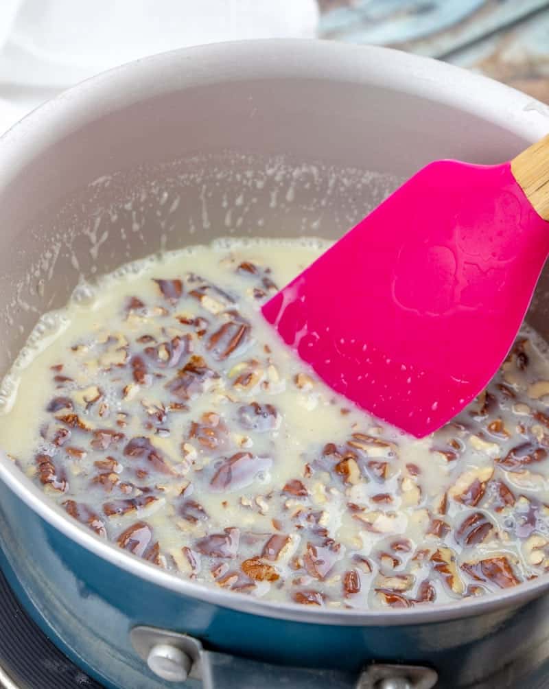 chopped pecans added to butter and sweetened condensed milk in a sauce pan