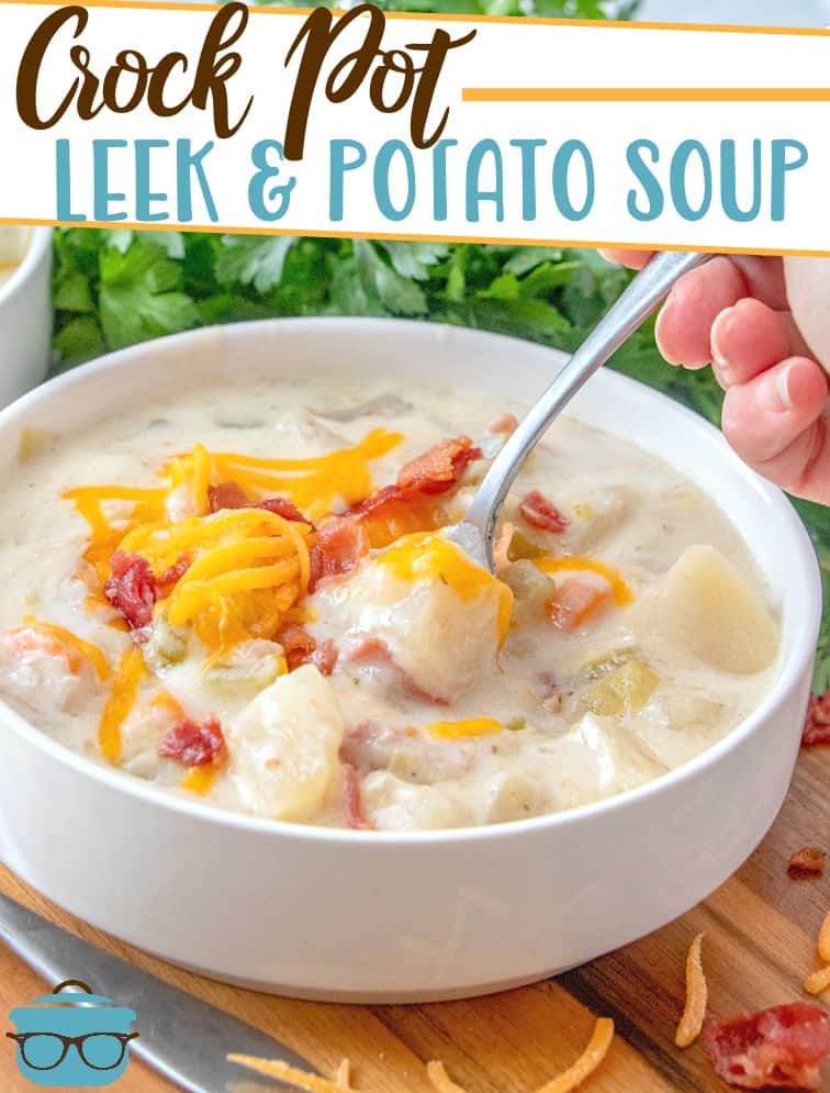 Crock Pot Leek and Potato Soup recipe from The Country Cook, pictured in a white bowl topped with shredded cheddar cheese and bacon pieces.