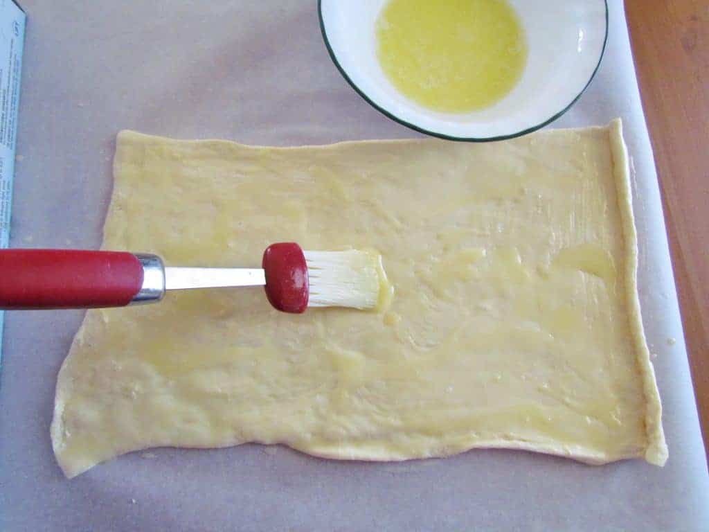 brushing crescent roll dough with melted butter
