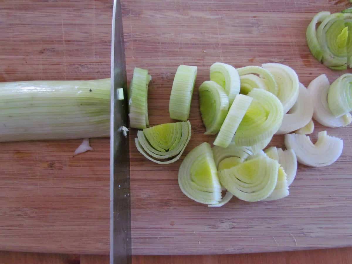 cutting and slicing leeks on a cutting board.