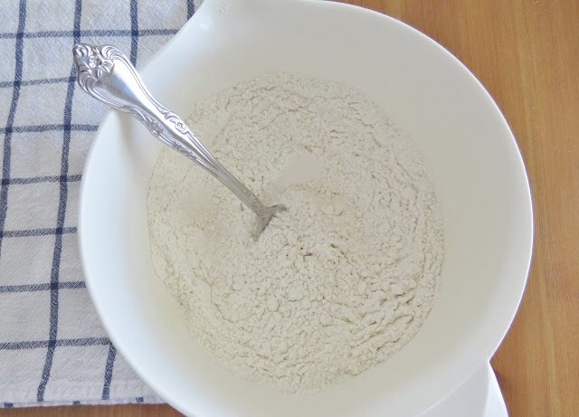 fork stirring flour mixture in a white mixing bowl