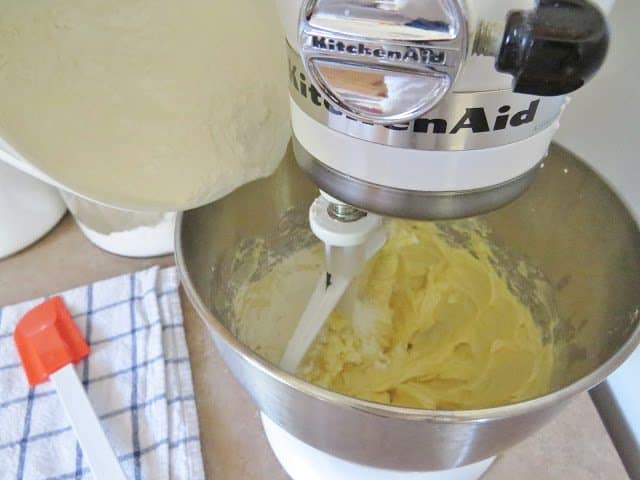 adding flour mixture to butter shortening in a metal bowl stand mixer.