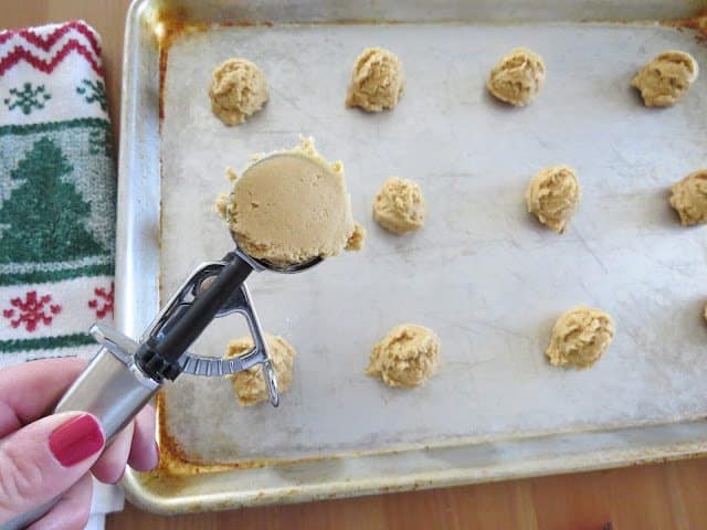 cookie scooper scooping up cookie dough batter.