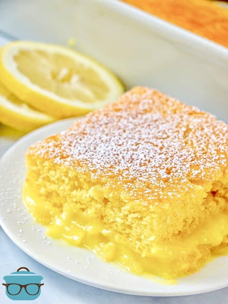 Warm Lemon Pudding Cake on a white plate with sliced lemons