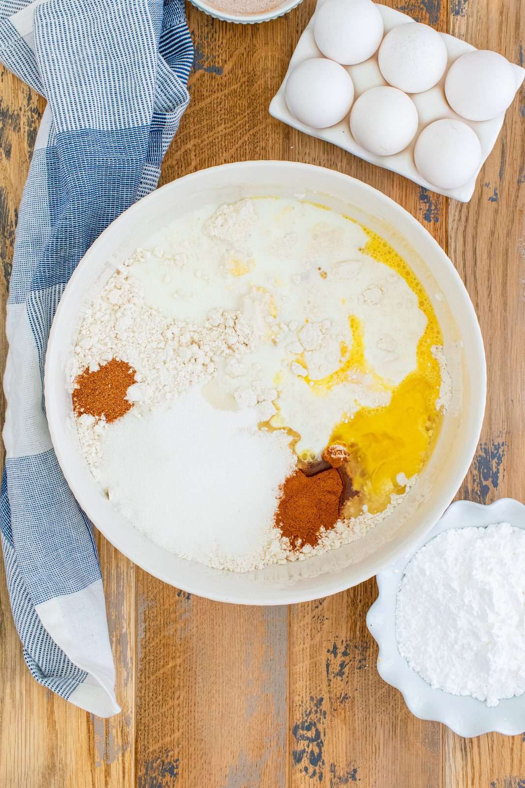 pancake mix, cinnamon, nutmeg, eggs and milk in a white bowl.