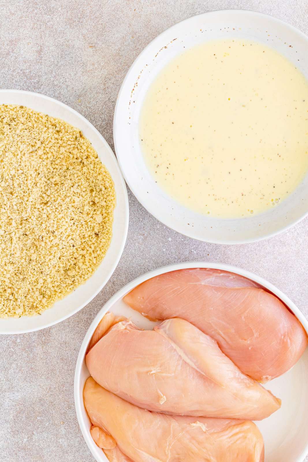 chicken in a bowl, panko bread crumbs in a separate bowl and egg/milk mixture in a third bowl.
