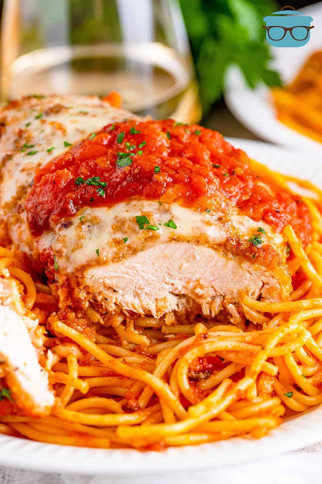 sliced of chicken breast served over spaghetti with sauce.