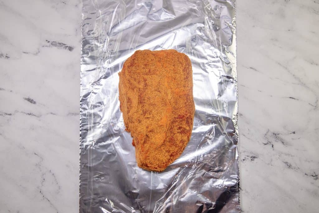 taco seasoning ruined into a chuck roast on a piece of aluminum foil.