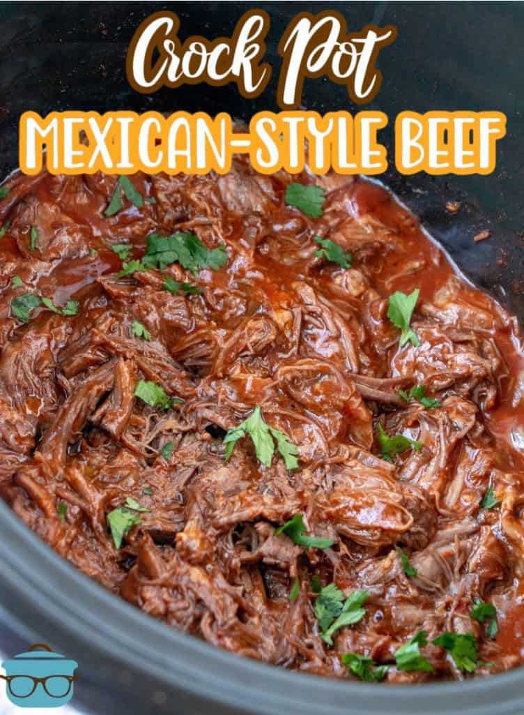 Crock Pot Mexican Shredded Beef recipe from The Country Cook, shredded beef shown in a slow cooker with chopped parsley sprinkled on top