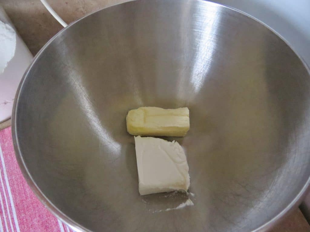 cream cheese and butter in the bottom of a silver mixing bowl