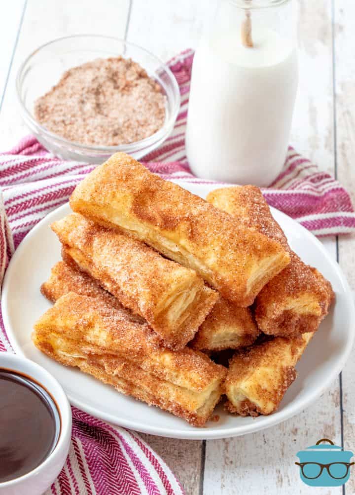 Puff Pastry Churros on a plate with a bottle of milk in the background. 