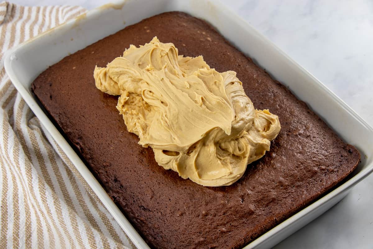 gently spreading peanut butter frosting on cooled chocolate cake.
