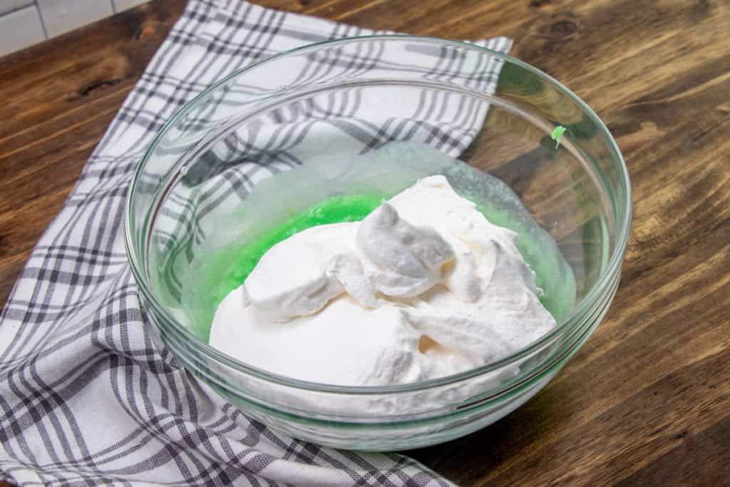 whipped topping added to pistachio pudding mixture in bowl