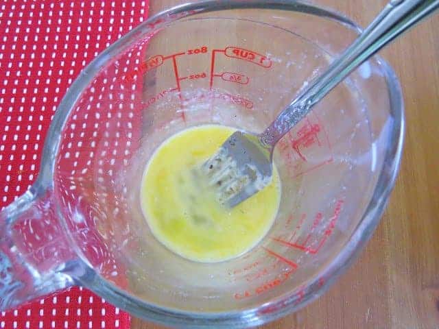 beaten egg in a measuring cup with a fork