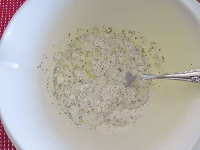 stirring egg into flour mixture in a white bowl