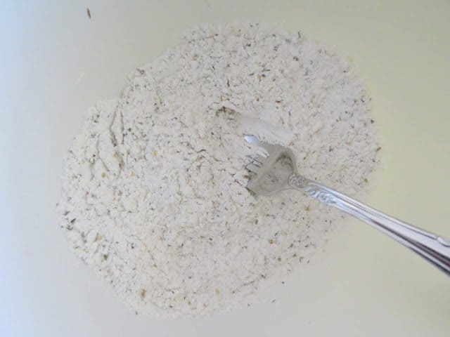 flour, baking powder, Italian seasoning in a white bowl with a fork