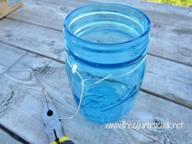 wire wrapped around the top of a blue mason jar and secured