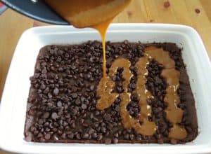 pouring melted caramel on top of chocolate chips.
