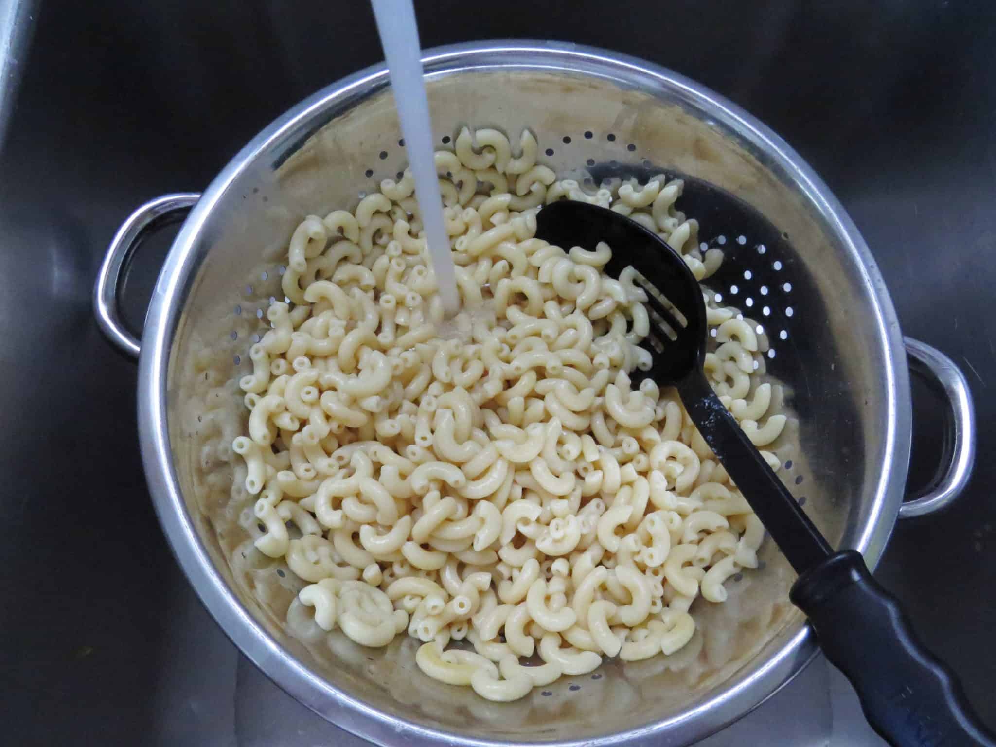 rinsing cooked macaroni in a strainer.