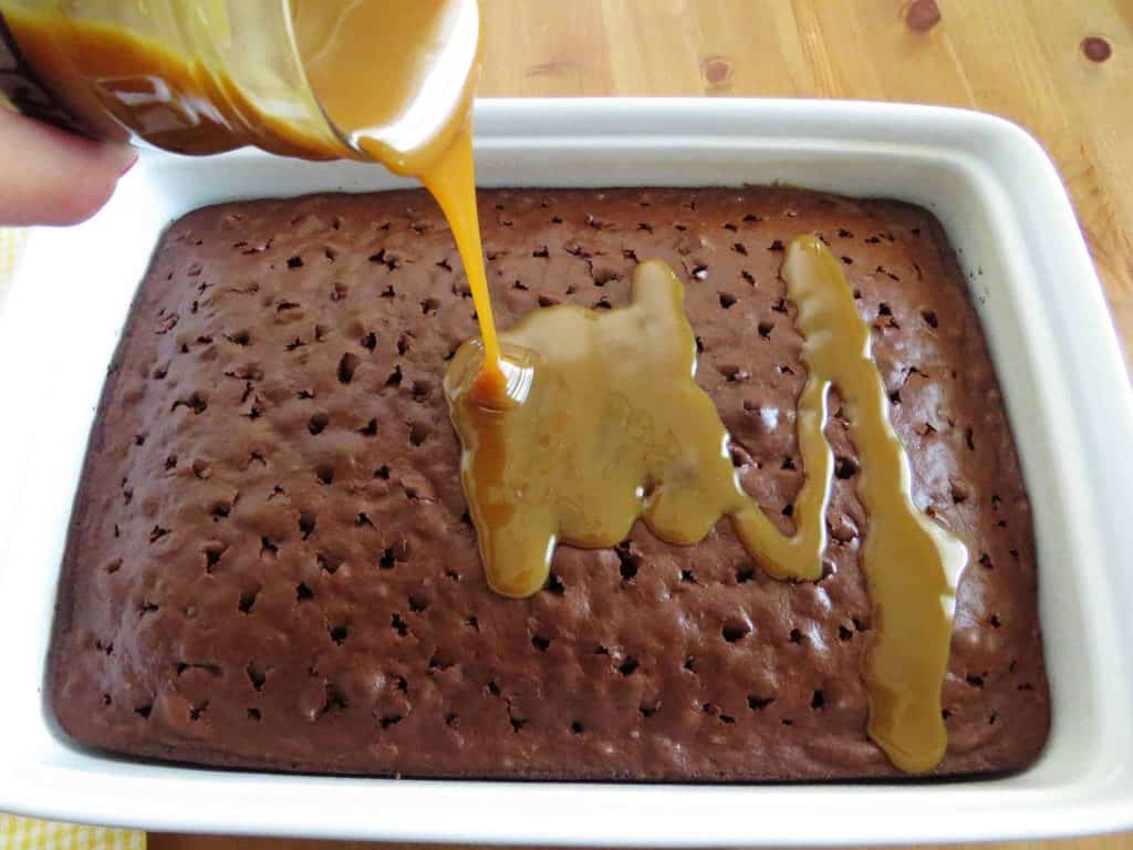 pouring jarred caramel sauce over warm chocolate cake