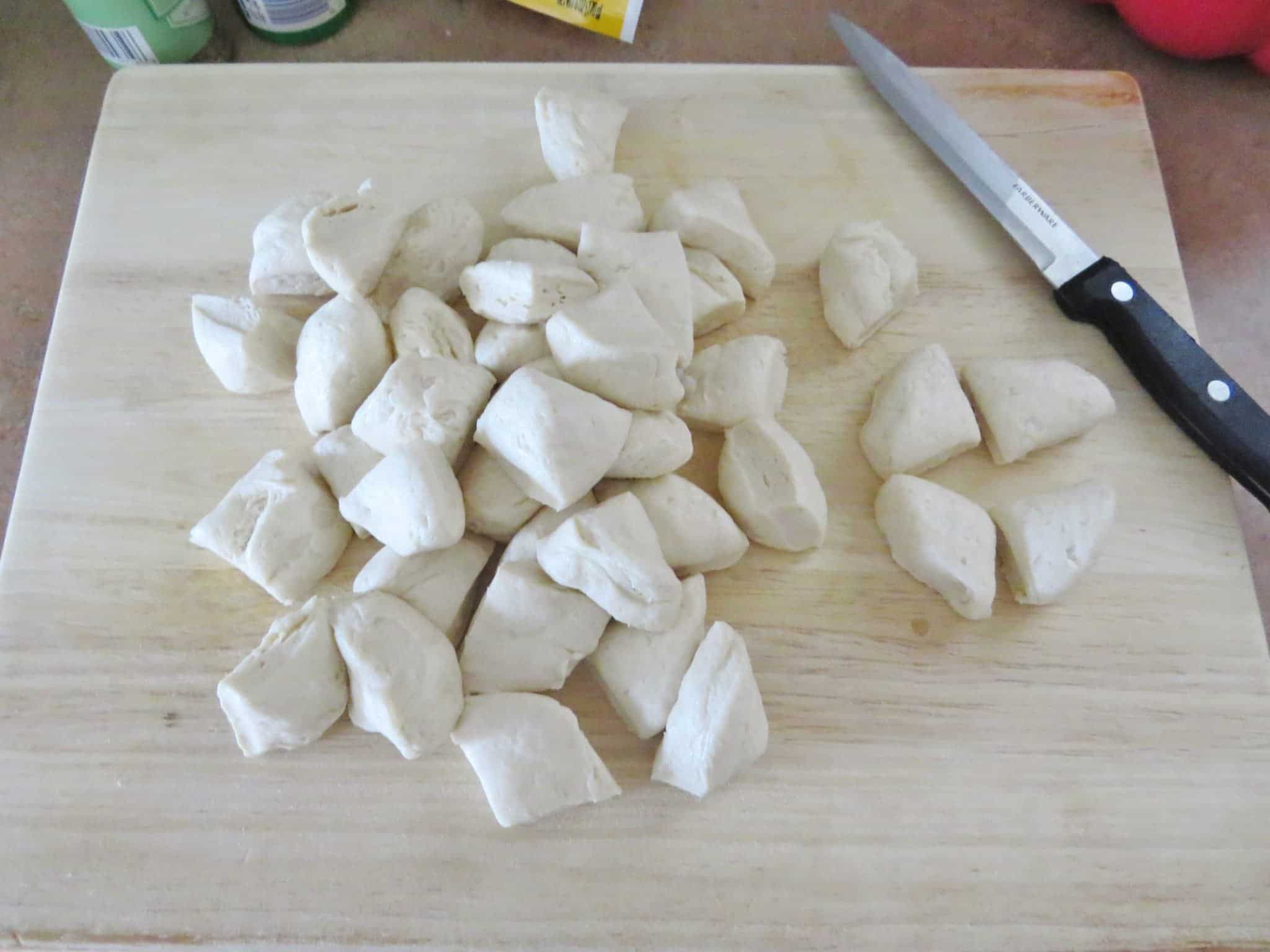 cut refrigerated Pillsbury biscuits on a wooden cutting board.