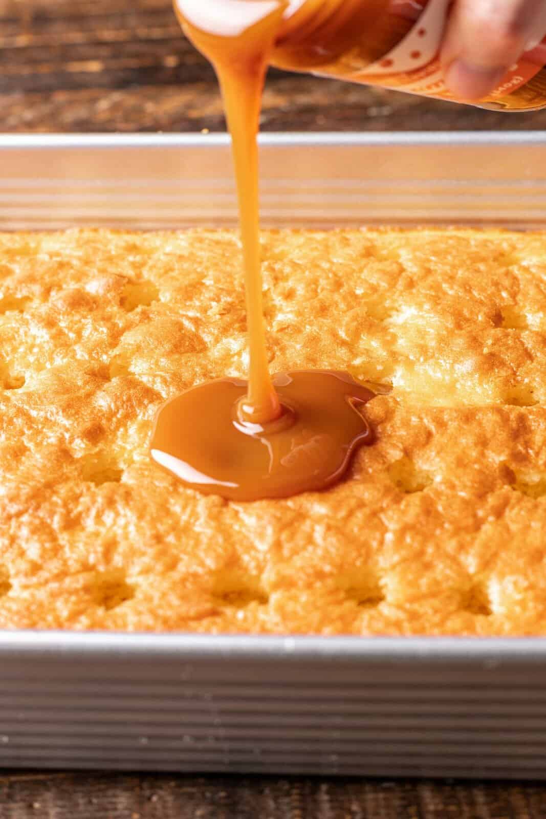 caramel sauce being poured into cake holes. 