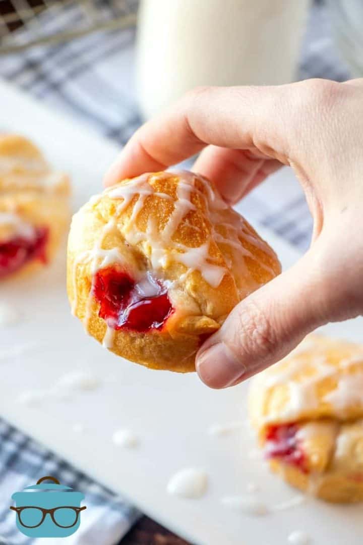 a cherry pie bite being held up by a hand.