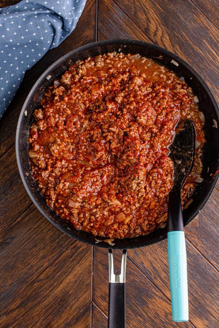 chili with ground beef, no beans in a skillet with a spoon.