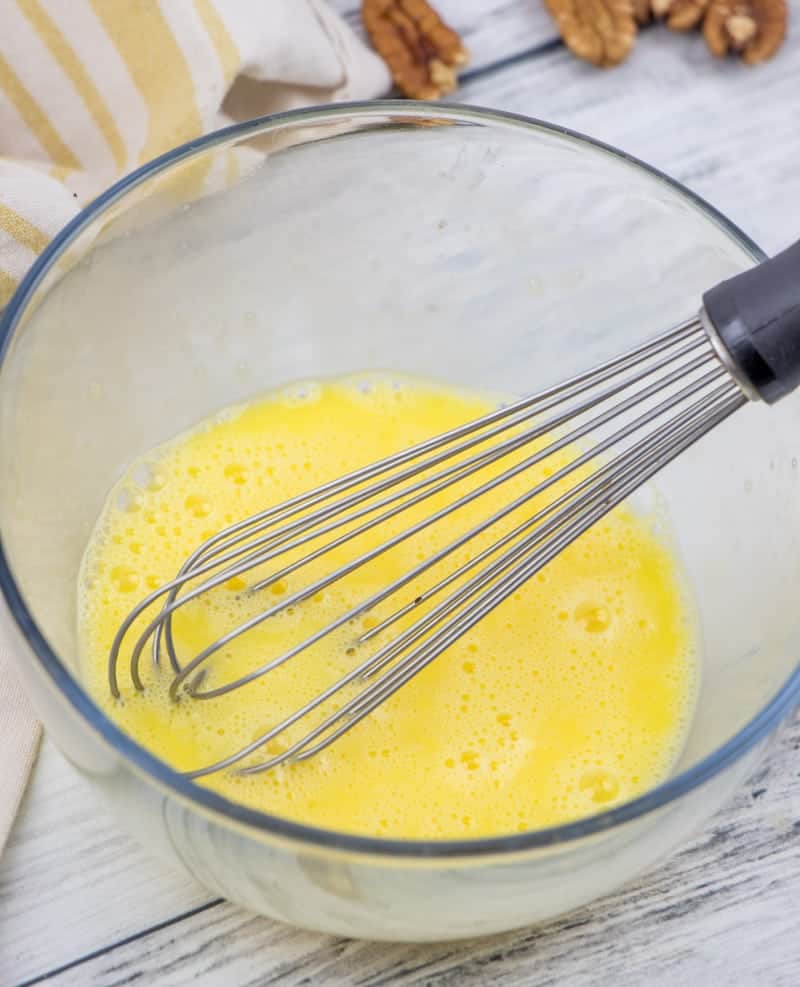 an egg being whisked in a clear bowl.
