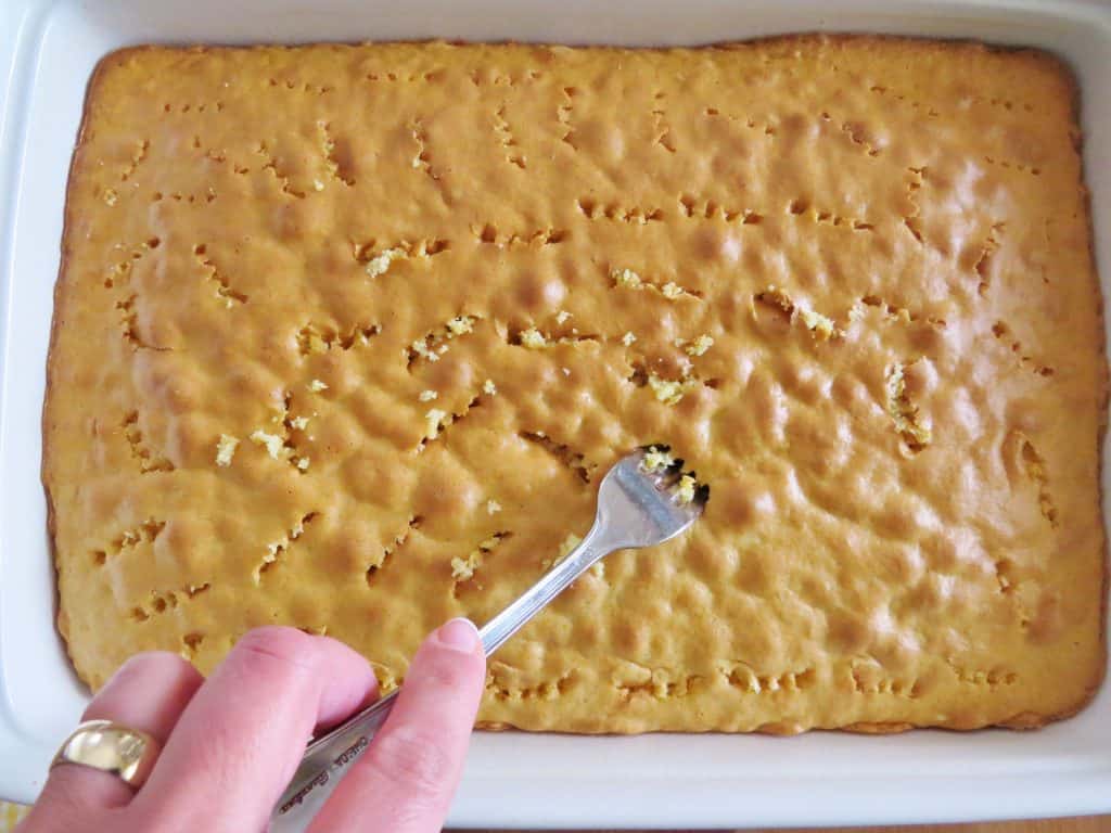 poking holes into a baked cake with a fork