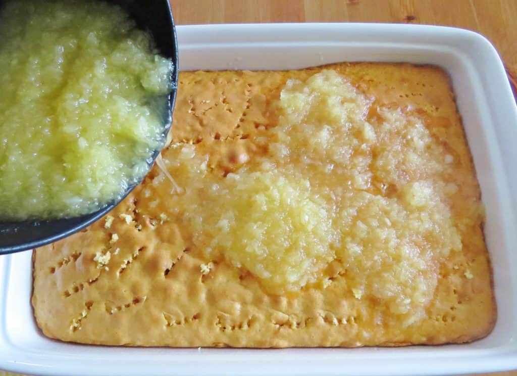 pouring crushed pineapple mixture into poked holes in cake