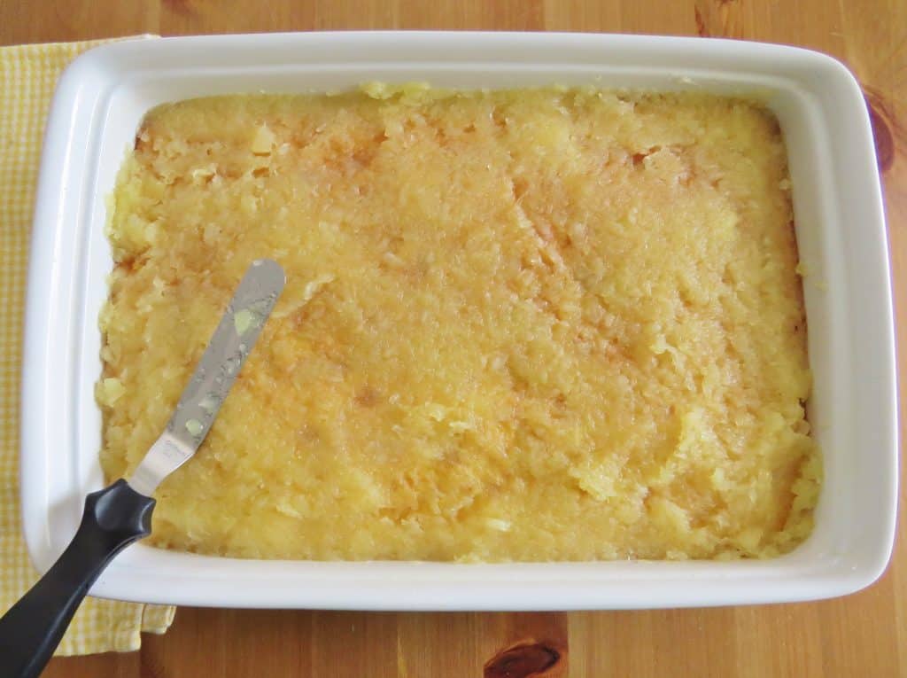 spreading pineapple mixture evenly over cake with an offset spatula