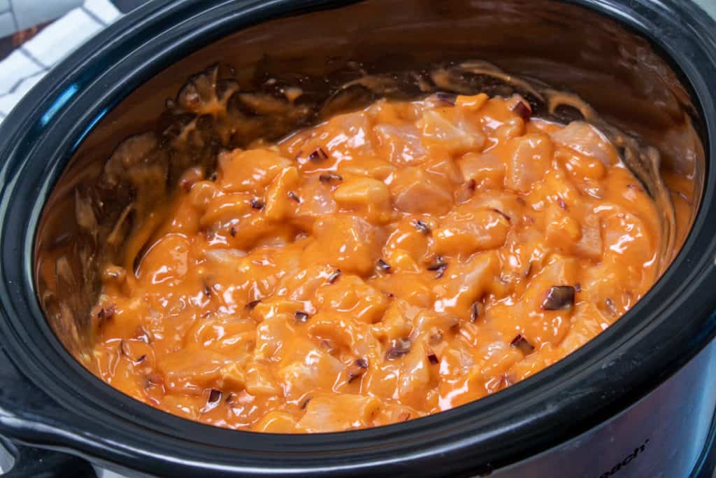 uncooked chicken breasts mixed with buffalo sauce and cream of chicken soup in a slow cooker
