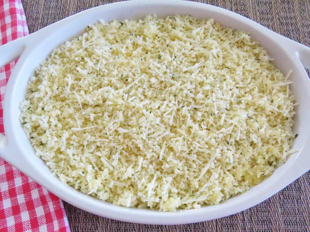 crumb topping mixture sprinkled on top of creamy dip mixture in an oval baking dish
