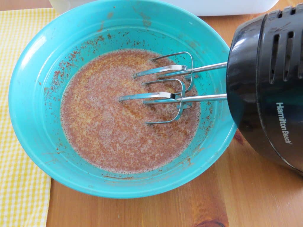 french toast batter in a blue bowl being mixed together with an electric hand mixer. 
