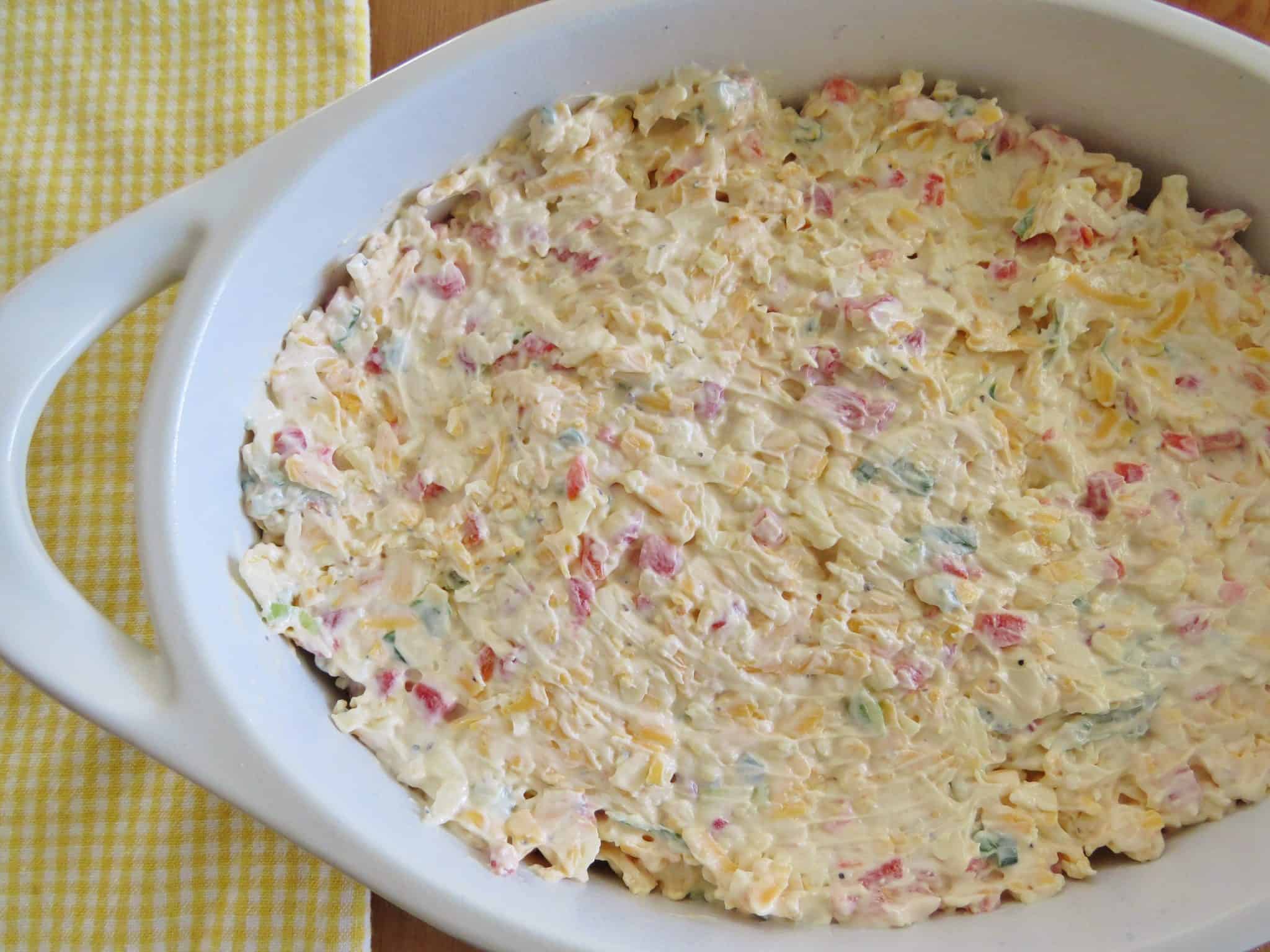 pimiento cheese dip mixture spread into an oval white baking dish.