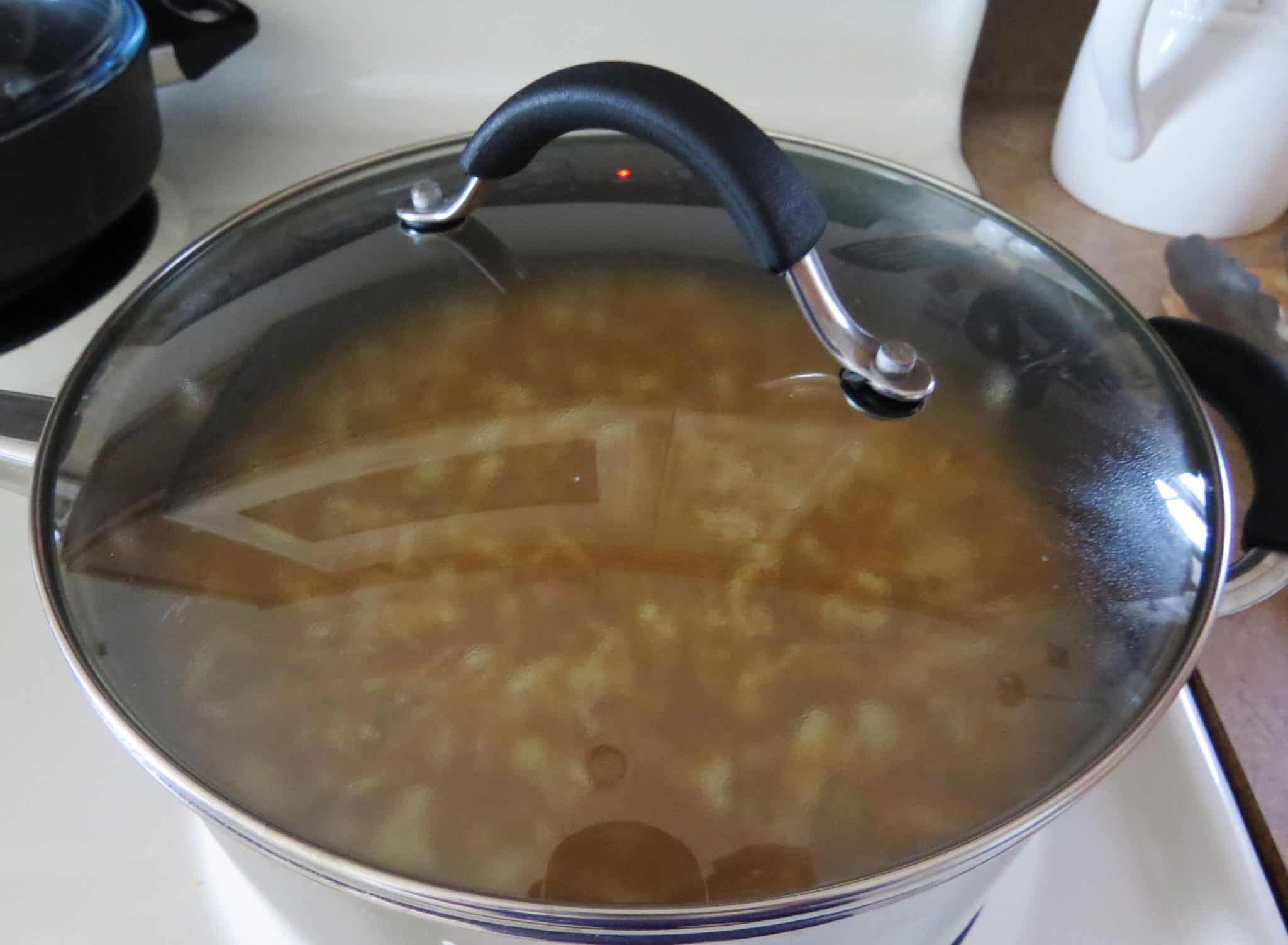 boiling chicken in chicken broth in a pot with a lid on top.