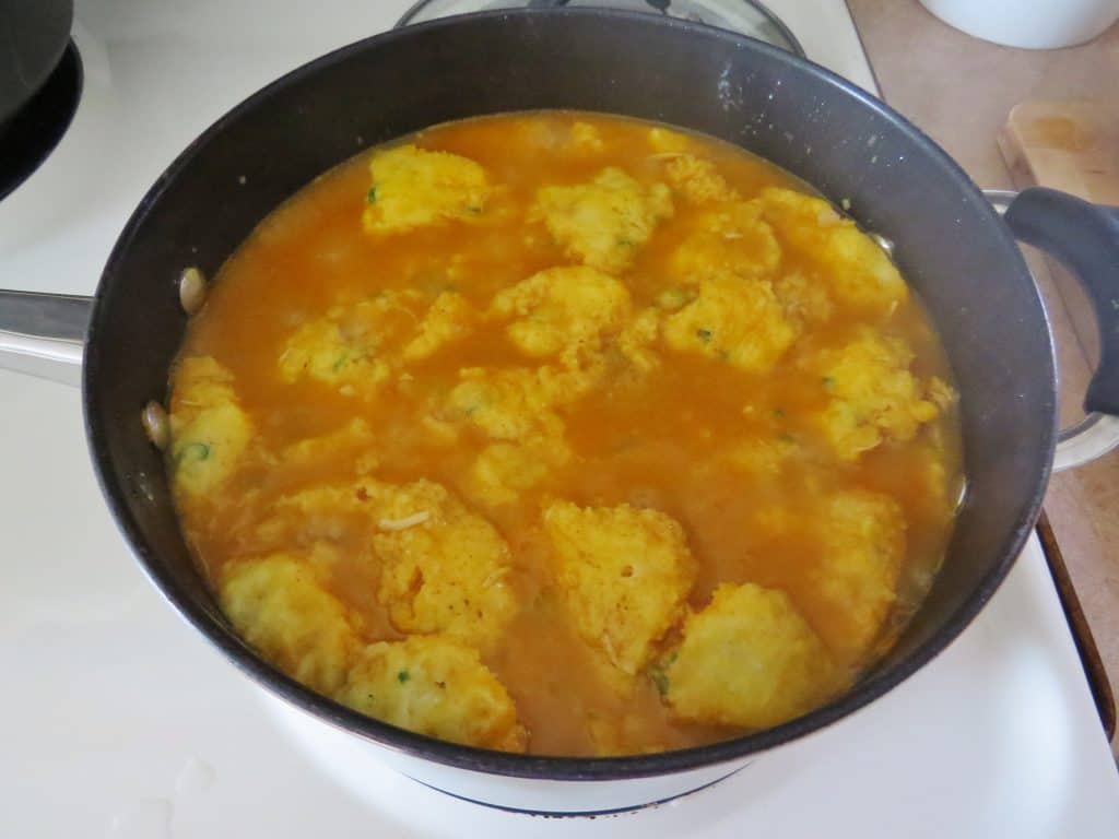 cornbread dumplings simmering in white chicken chili broth. 