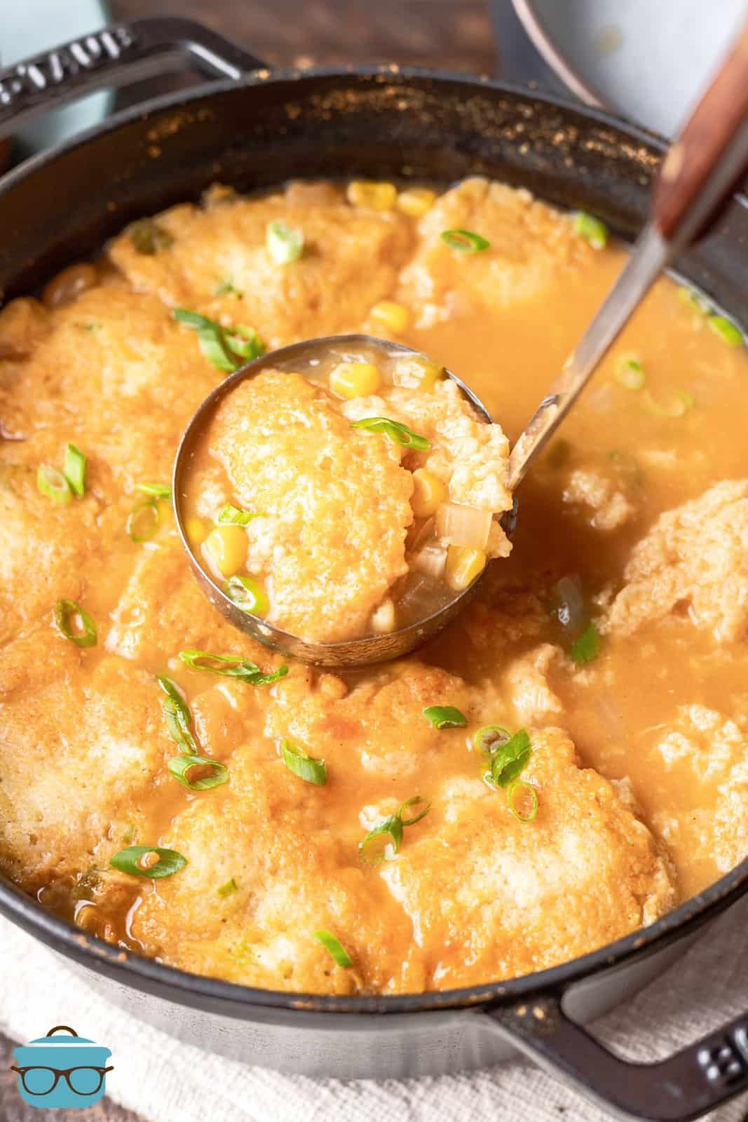 a ladle scooping up some cornbread dumplings out of a large pot. 