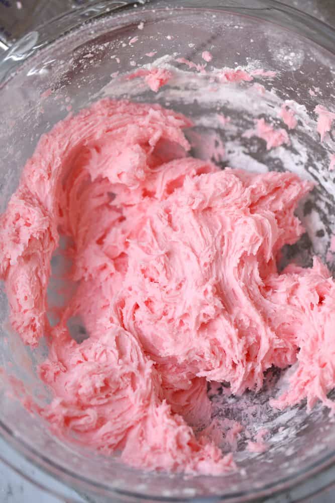 milk, powdered sugar, cream cheese, mint extract, red food coloring mixed together with an electric mixer in a bowl