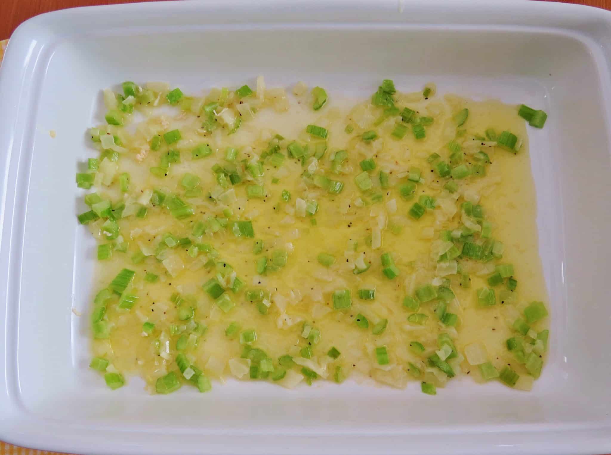 melted butter, cooked diced celery and onion layered into the bottom of a large white baking dish.