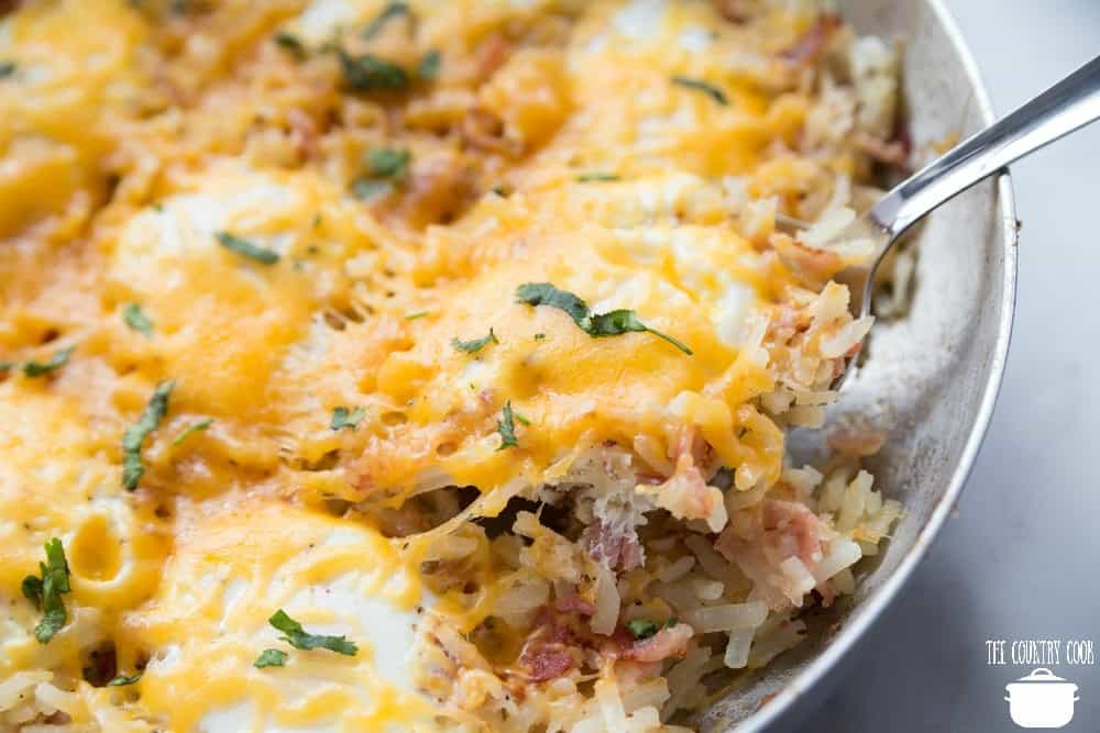 Cowboy Hash Brown Casserole recipe with eggs, cheese, bacon, onion in a large skillet.