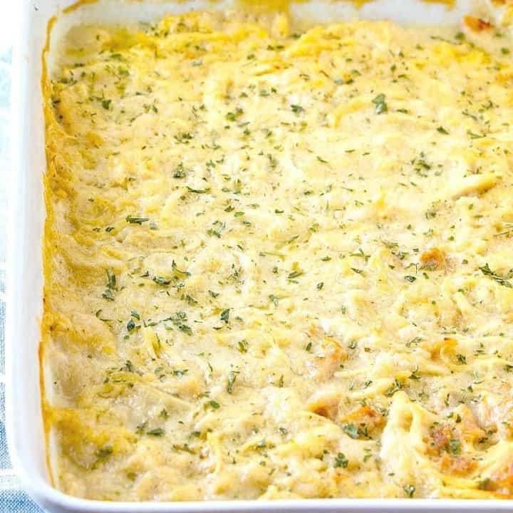 fully cooked chicken and dumplings casserole in a white baking dish topped wih chopped parsley