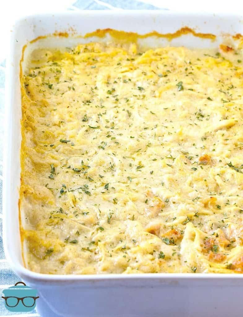 fully cooked chicken and dumplings casserole in a white baking dish topped wih chopped parsley