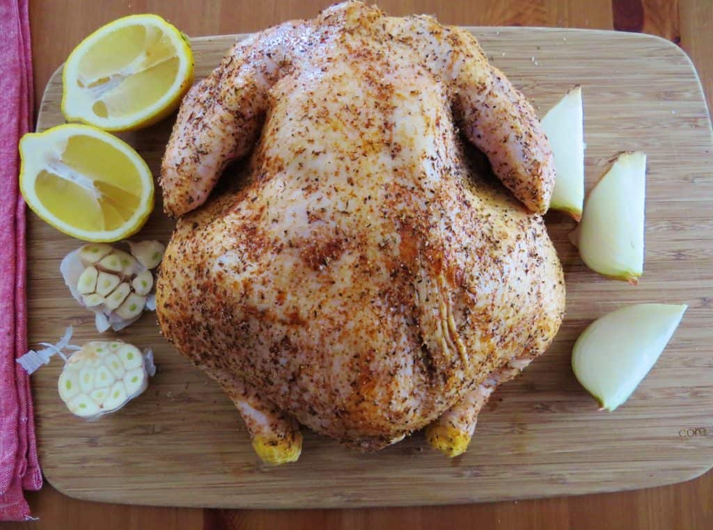 seasoned whole chicken with slices of onion, lemons and garlic