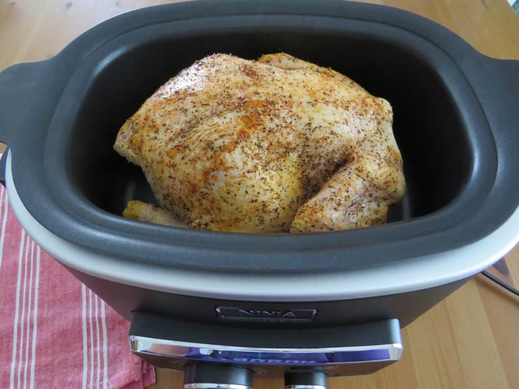seasoned whole chicken in an oval 6-quart slow cooker
