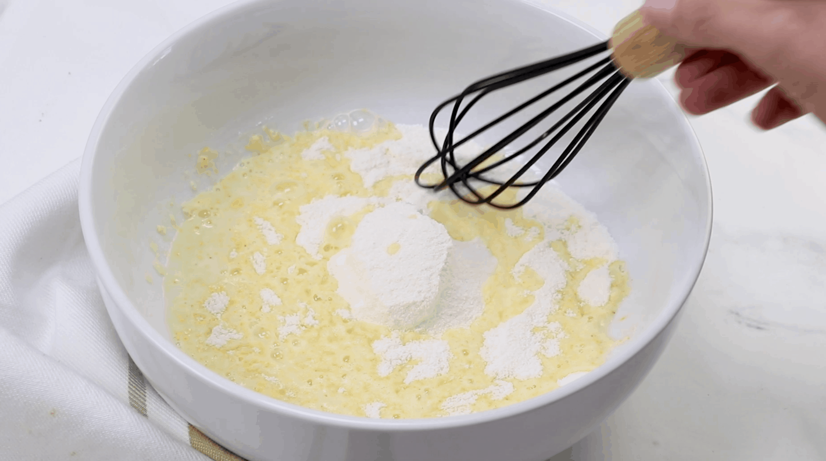 instant pudding and milk mixed together in a white bowl with a whisk.
